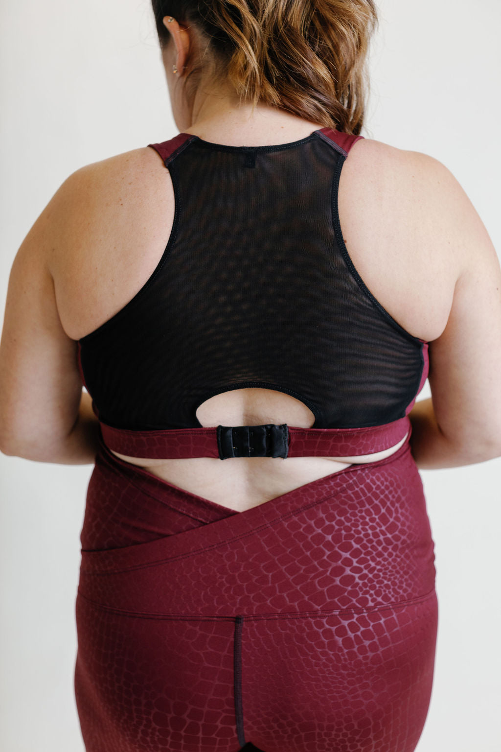 Fig colored maternity activewear nursing sports bra with mesh-back design and an adjustable band with hooks.